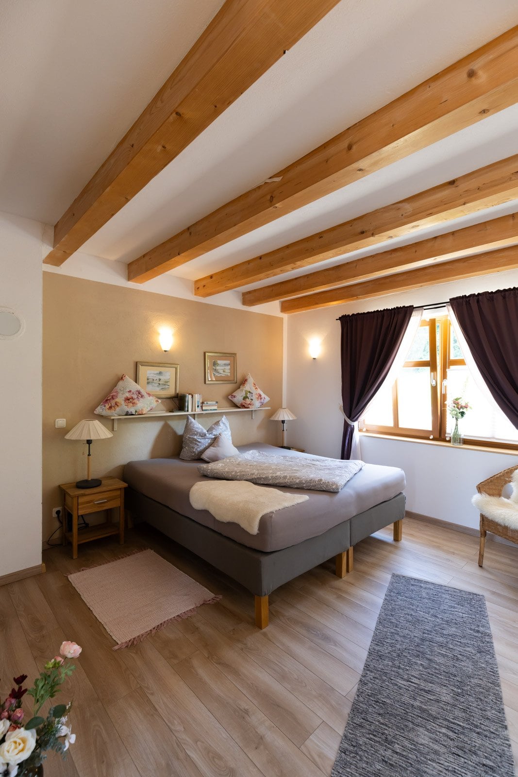 Helles Gästezimmer mit Holzbalken und Doppelbett